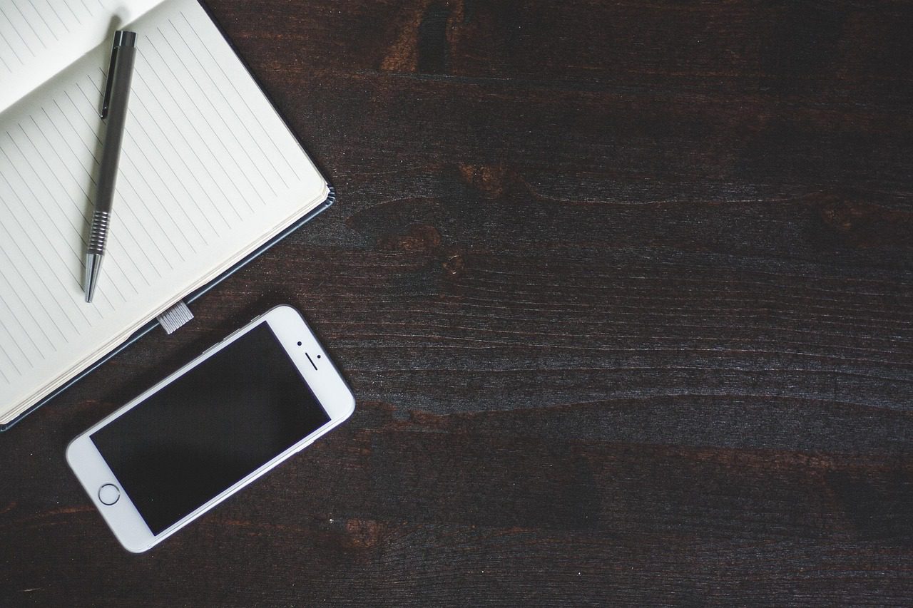 Diversos acessórios para celular como fones de ouvido, cabos e capas organizados sobre uma mesa clara.
