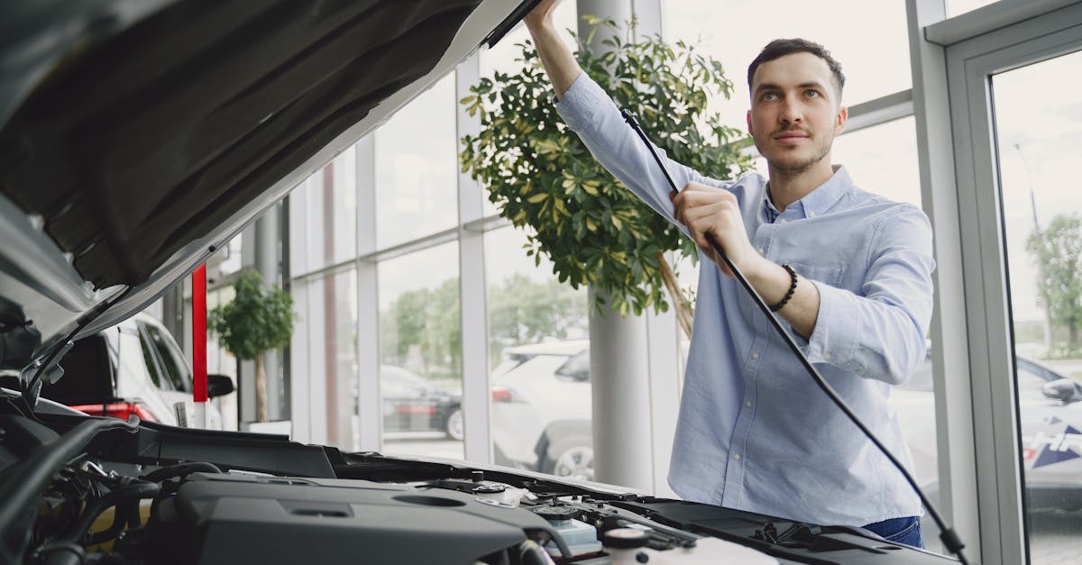 A man carefully checking a car engine in a bright, modern car showroom.
