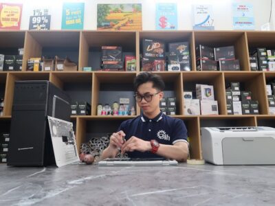 Young technician fixing a computer in a modern electronics store setting.