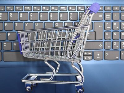 A miniature shopping cart placed on a laptop keyboard symbolizing online shopping and e commerce.