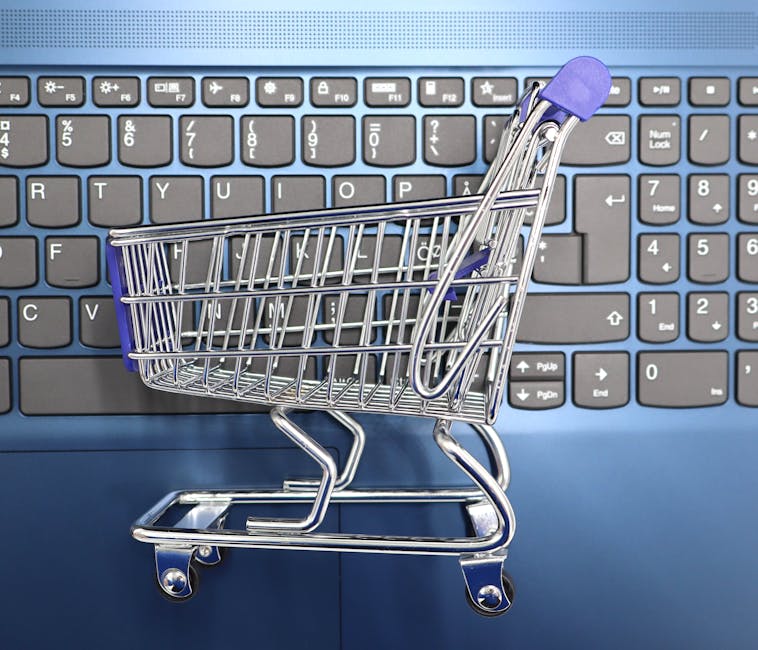 A miniature shopping cart placed on a laptop keyboard symbolizing online shopping and e commerce.