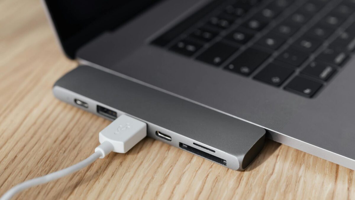 Hub USB-C multiportas conectado a laptop moderno sobre mesa de madeira, demonstrando conectividade para home office e produtividade
