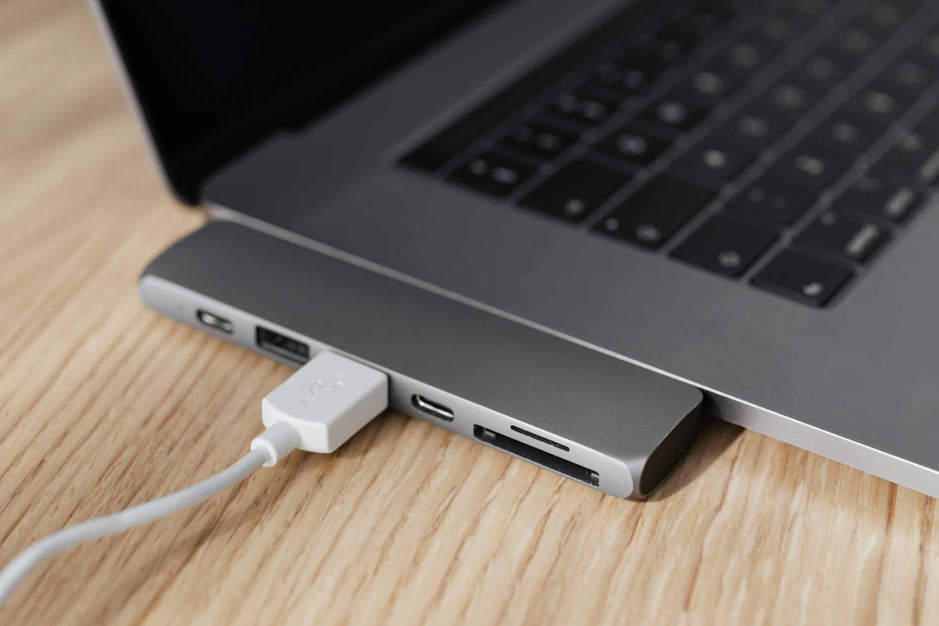 Hub USB-C multiportas conectado a laptop moderno sobre mesa de madeira, demonstrando conectividade para home office e produtividade