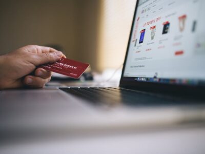 Pessoa segurando cartao de credito fazendo compra online no laptop
