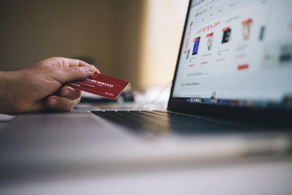 Pessoa segurando cartao de credito fazendo compra online no laptop