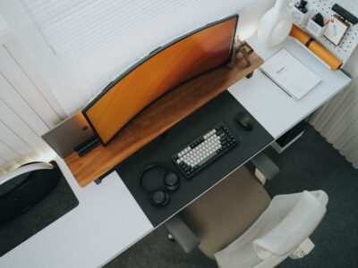 Top view of a stylish modern office desk setup featuring a curved monitor and keyboard.