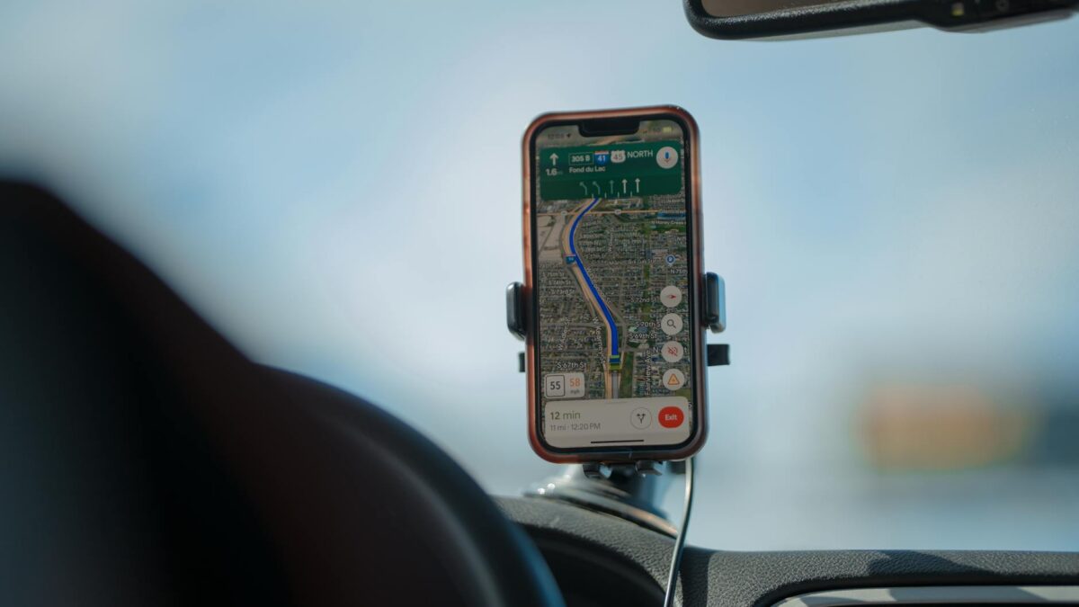 Smartphone com GPS montado em suporte veicular magnetico no painel do carro durante viagem, demonstrando navegacao segura ao volante