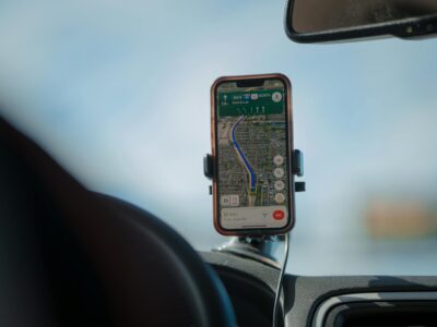 Smartphone com GPS montado em suporte veicular magnetico no painel do carro durante viagem, demonstrando navegacao segura ao volante