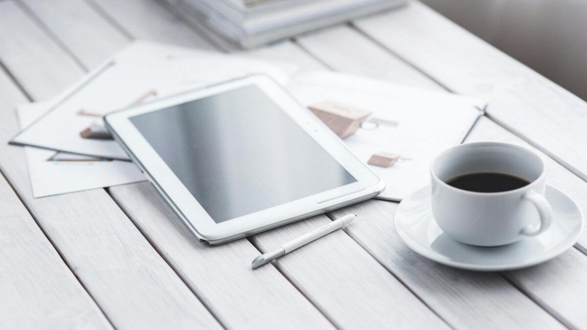 Tablet moderno com stylus e cafe sobre mesa de escritorio, demonstrando versatilidade para estudos, trabalho e lazer em 2026